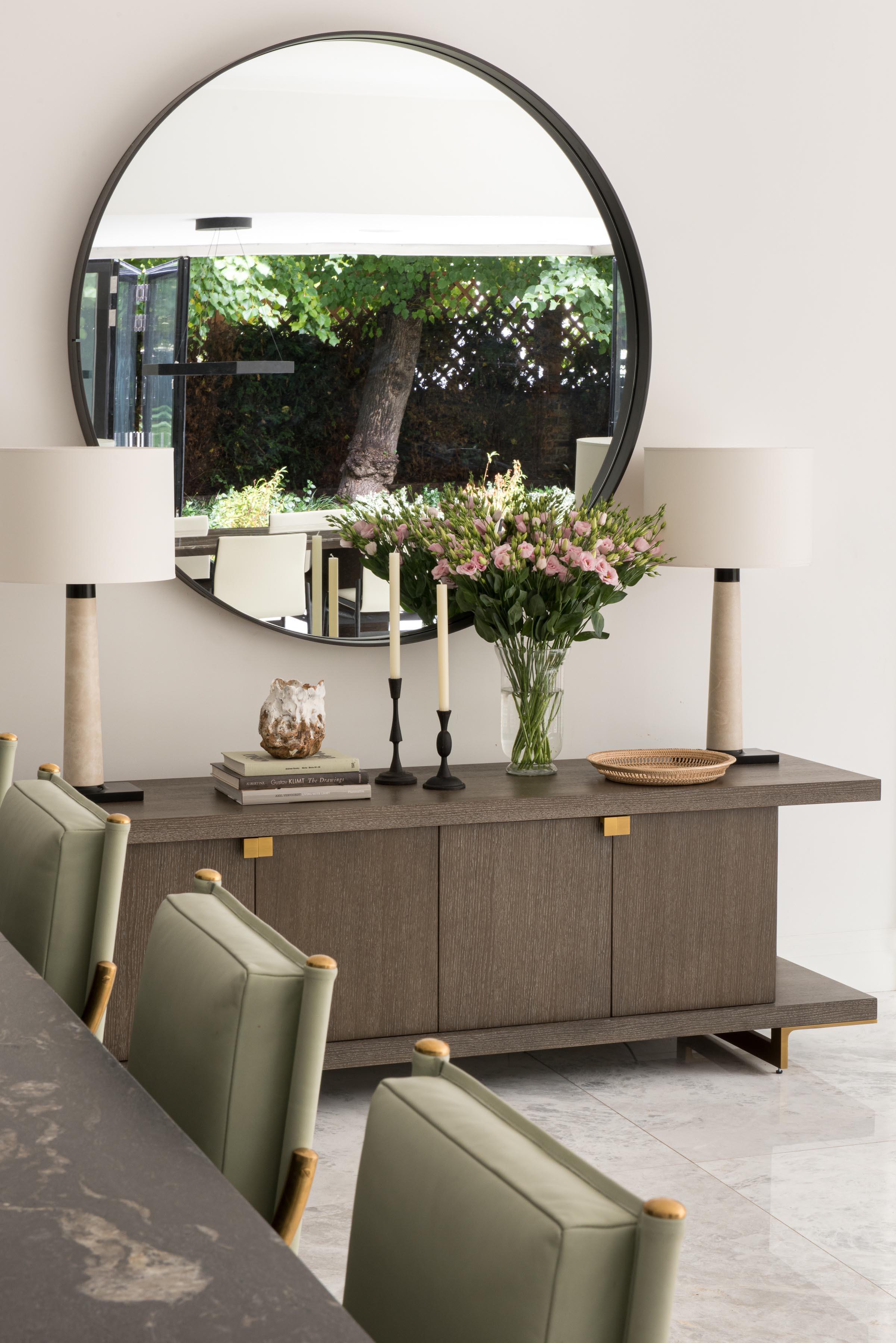An elegant dinging room designed by Louise Wicksteed Interiors featuring green leather armchairs and marble table